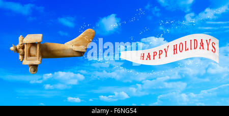 Vintage Holz Spielzeug Flugzeug fliegen in blauen Himmel ziehen einen Happy Holidays-banner Stockfoto