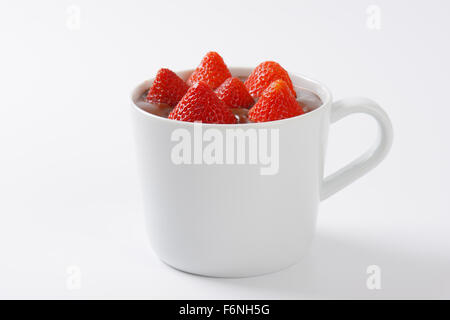 Becher Erdbeeren in Schokolade Pudding auf weißem Hintergrund Stockfoto