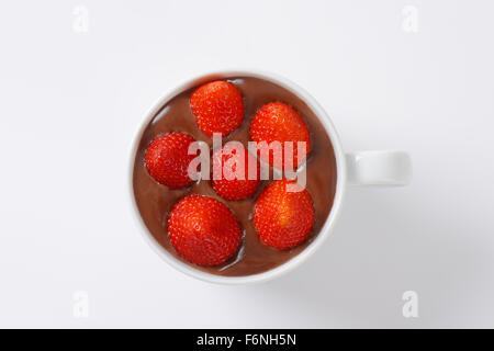 Becher Erdbeeren in Schokolade Pudding auf weißem Hintergrund Stockfoto