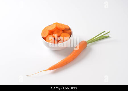 Schüssel mit in Scheiben geschnittenen frischen Karotten auf weißem Hintergrund Stockfoto