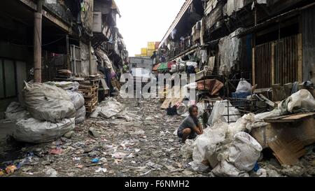 Manila, Philippinen. 14. November 2015. Eine Frau sucht ihren gesammelten Haufen Müll für benutzbare Gegenstände in einer Straße im Stadtteil Tondo Slum in Manila, Philippinen, 14. November 2015. Foto: Girlie Linao/Dpa/Alamy Live News Stockfoto