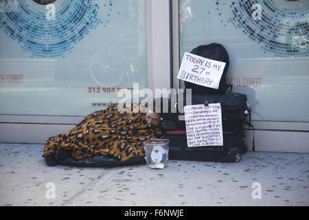 Obdachlose Frau streckt um Hilfe an ihrem 27. Geburtstag, schlafen auf dem Bürgersteig auf der 34th Street in Midtown Manhattan, NYC. Stockfoto