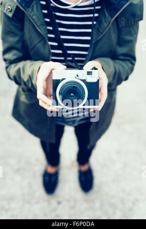 Junge hübsche Frau hält einen Vintage-Kamera - Fotografie, kreatives Konzept - Fokus auf die Kamera Stockfoto