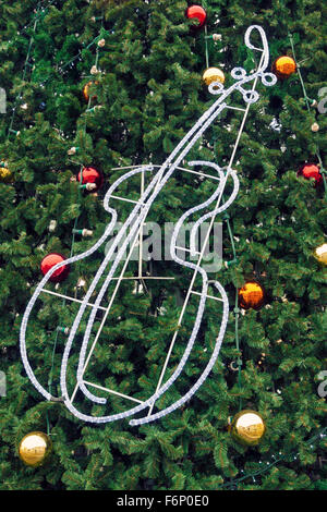 Weihnachten Hintergrund der öffentlichen Weihnachtsbaum mit roten und gelben Kugeln und Violine dekoriert aus leuchtenden LED-Streifen. Stockfoto