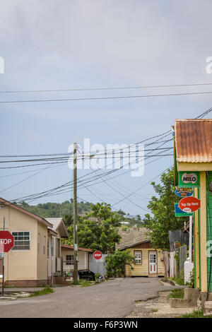 Vielzahl von Telefon und Strom Kabel Kreuz auf dem Dach Höhe zwischen den kleinen Geschäften und Häusern in Gros Islet, St. Lucia. Stockfoto