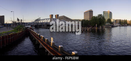 Panorama-Blick auf die moderne Oosterdok Drehbrücke über den Oosterdok-Kanal bei Sonnenuntergang in Amsterdam (Niederlande) Stockfoto