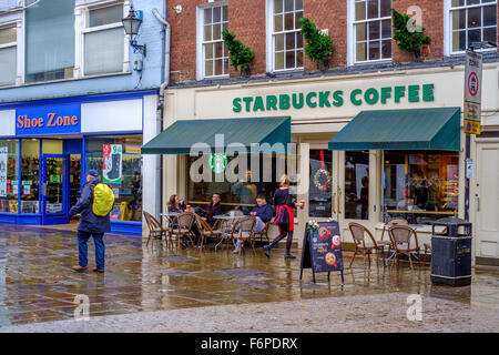 Menschen saßen draußen Starbucks Café an einem regnerischen Tag in Salisbury Wiltshire Vereinigtes Königreich Stockfoto
