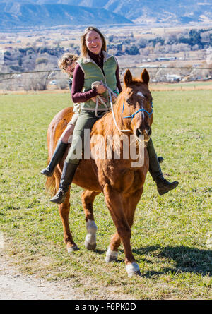 Attraktive Mutter und seinem kleinen Sohn Reiten auf der Ranch Weide Stockfoto