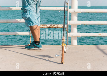 Ein Mann setzen seine Angelrute auf dem Boden und warten auf Fische Stockfoto