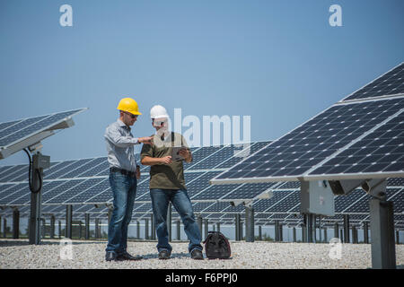 Kaukasische Techniker sprechen in der Nähe von Sonnenkollektoren Stockfoto