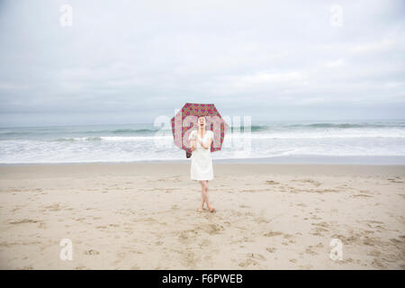 Frau mit Sonnenschirm am Strand lachen Stockfoto