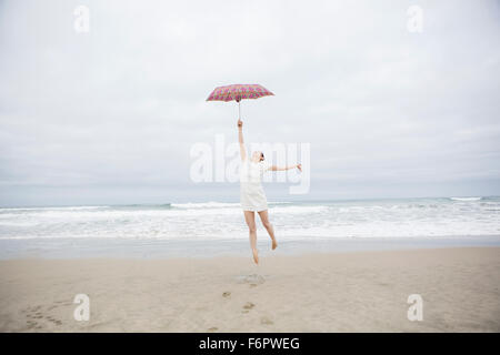 Frau mit Sonnenschirm am Strand spielen Stockfoto