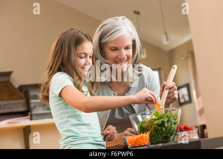 Kaukasische Großmutter und Enkelin machen Salat in Küche Stockfoto