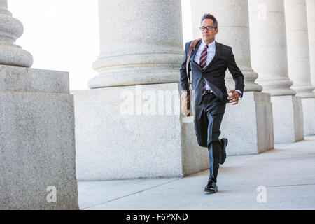 Gemischte Rassen Geschäftsmann laufen unter Spalten Stockfoto