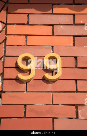 Die Nummer 99 auf Ziegel Wand Hintergrund Stockfoto