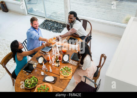 Freunde am Esstisch Toasten Stockfoto