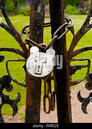 Vorhängeschloss und Metall Kette sichern ein schmiedeeisernes Tor Stockfoto