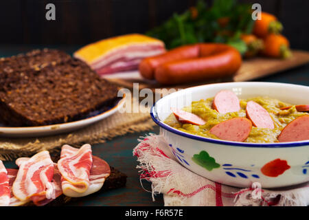 Herzhafte traditionelle holländische Erbsensuppe mit geräucherter Wurst, Roggenbrot und Speck. Oder: 'Erwtensoep met Rookworst, Roggebrood En Spek'. Stockfoto