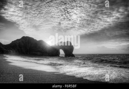 Winter-Sonnenaufgang hinter Durdle Door auf Jurassic Coast in schwarz / weiß Stockfoto