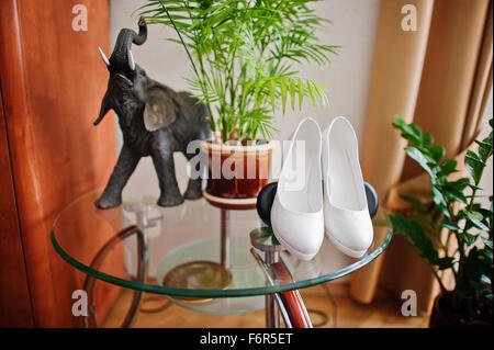 weiße Bräute Schuhe am Glastisch Stockfoto