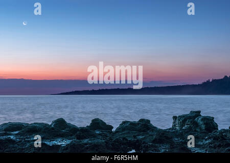 Sonnenaufgang über Felsformationen am Strand Stockfoto