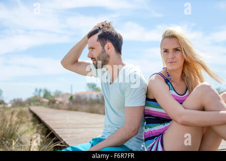 Porträt des jungen Paares am Strand mit Blick traurig Stockfoto