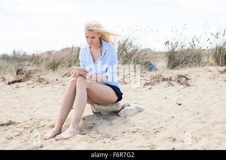 Junge Frau mit digital-Tablette am Strand Stockfoto