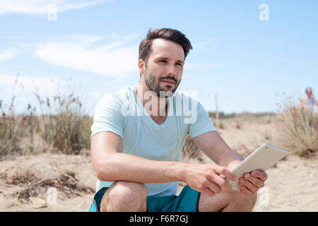 Junger Mann mit digital-Tablette am Strand Stockfoto