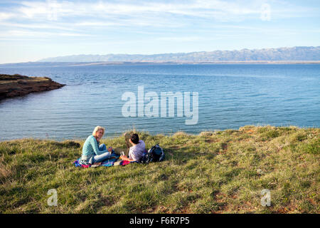 Junges Paar mit einem Picknick am Ufer Stockfoto