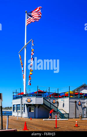 Nautische Wimpel und die amerikanische Flagge fliegen über Longboards Grill-Restaurant am Ende des Stearns Wharf in Santa Barbara Stockfoto