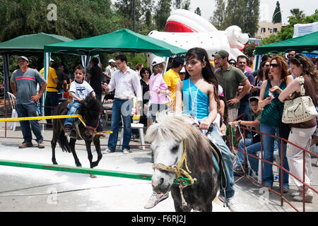 Reiten auf Pferd frohe Kinder Ponyreiten gehen um junges Mädchen gefesselte auf Jahrmarktsattraktion UK England Stockfoto