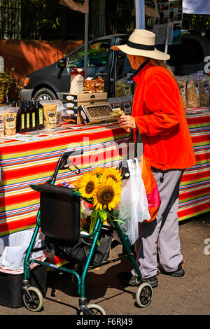 Ältere Frau mit ihrem Fuß Rahmen kaufen frischen Gemüse und Sonnenblumen aus dem wöchentlichen Bauernmarkt in Santa Barbara in Neff Stockfoto