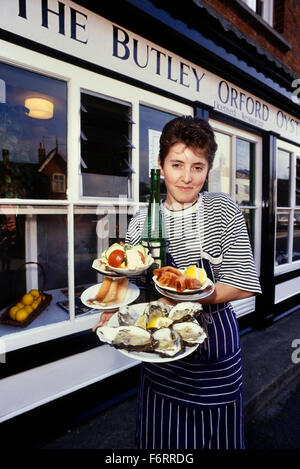 Eine Kellnerin, hält eine Auswahl an frischen Austern und Räucherfisch an der Butley Orford Oysterage. Suffolk. England. UK Stockfoto