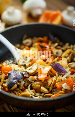 gebratene Champignons mit Paprika und Zwiebeln in einer Pfanne erhitzen Stockfoto