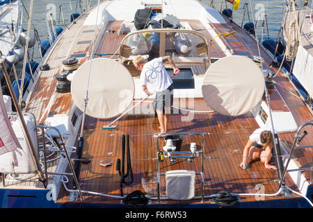 Junge männliche und weibliche Besatzungsmitglieder schrubben Deck des Luxus-yacht Stockfoto