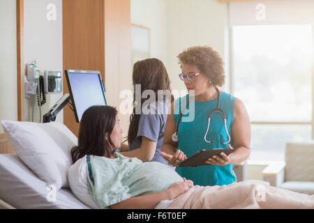 Arzt im Gespräch mit schwangeren Patienten im Krankenzimmer Stockfoto