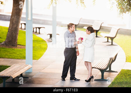 Hispanic Mann, Freundin Blumen im park Stockfoto