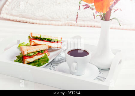 Frühstück am Holztablett im Bett Sandwich und Kaffee Stockfoto