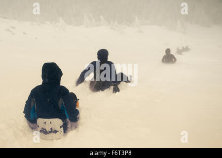 Kaukasische Wanderer Rodeln auf verschneiten Hügel Stockfoto