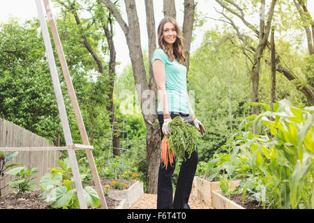 Kaukasische Frau mit Karotten im Garten Stockfoto