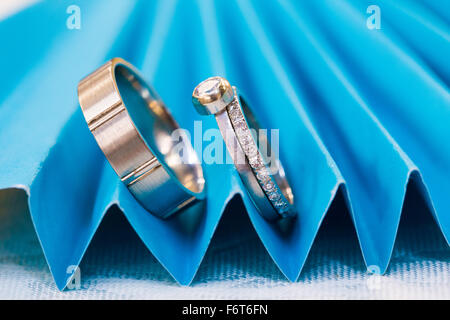 Braut und Bräutigam Hochzeit Ringe vor der Zeremonie auf einem blauen Ventilator fotografiert. Stockfoto