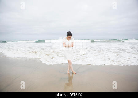 Frau, die in der Nähe von Wellen am Strand Stockfoto