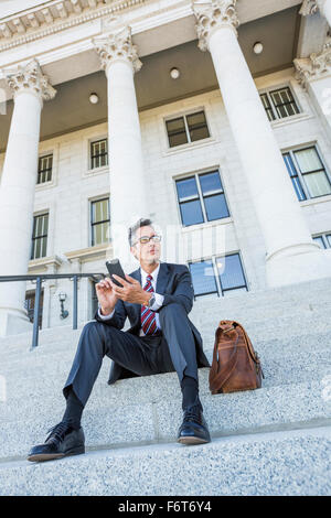 Gemischte Rassen Geschäftsmann mit Handy auf Gerichtsgebäude Schritte Stockfoto