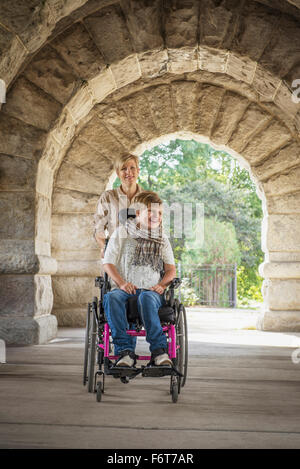 Mutter schob Querschnittsgelähmten Tochter im Rollstuhl Stockfoto