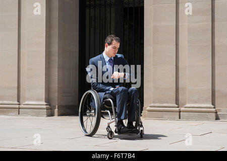 Querschnittsgelähmt Geschäftsmann im Rollstuhl Überprüfung Uhr Stockfoto