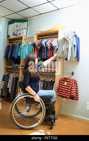Schwangere querschnittsgelähmt im Rollstuhl im Baby-Shop einkaufen