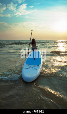 Frau zieht Paddleboard in See Stockfoto