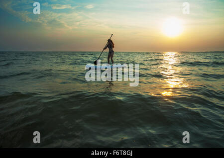 Frau stehend auf Paddleboard in See Stockfoto