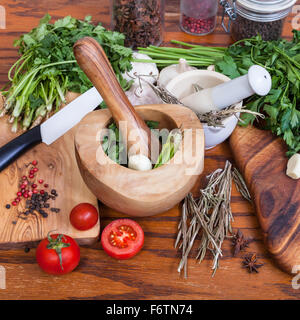 Kochen Gewürze - Mörser, Greens und getrocknete Gewürze auf Holztisch Stockfoto