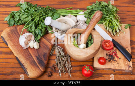 Kochen Gewürze - Mörser und frischen Kräutern auf Holztisch Stockfoto
